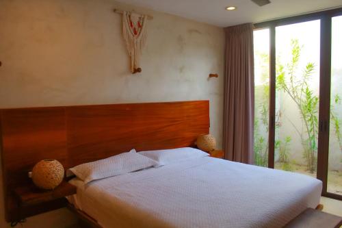 a bedroom with a bed with a wooden headboard and a window at Lipsos Private Luxury Beachfront home in Progreso