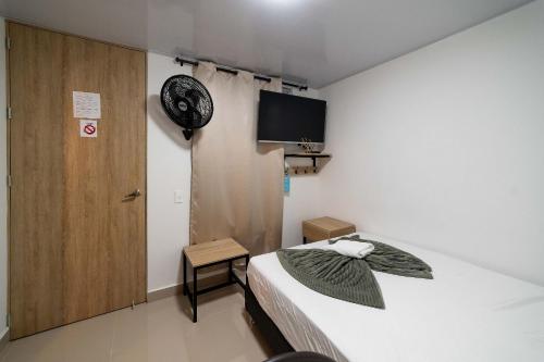 a room with a bed and a door and a tv at Hotel Doxa in Medellín
