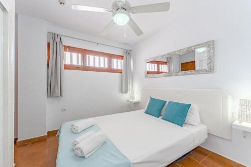a white bedroom with a bed and a ceiling fan at Costa Adeje Garden City Sea View in Csta Adje