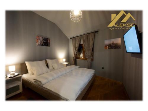 a bedroom with a large white bed and a flat screen tv at Aleksei Apartmani in Belgrade