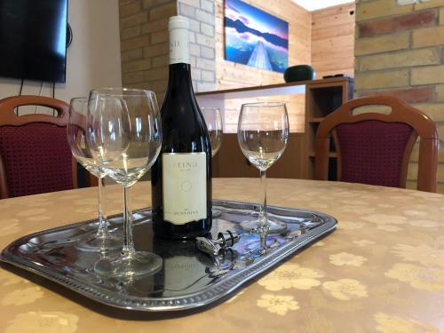 a bottle of wine sitting on a tray with two wine glasses at Harcsási 60 Vendégház in Békésszentandrás