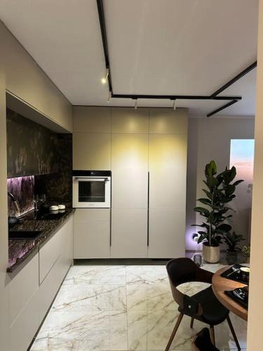 a kitchen with white cabinets and a table and a chair at Wood & Stone Apartment in Gdańsk