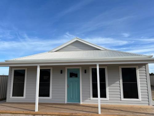 a white house with a blue door at Foxhill Shores - WIFI outside pets in Robe