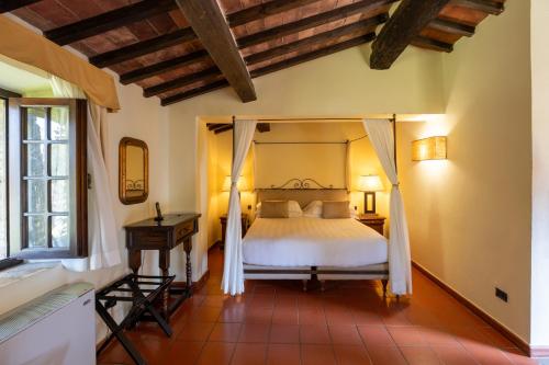 a bedroom with a canopy bed and a desk at Borgo San Luigi in Monteriggioni