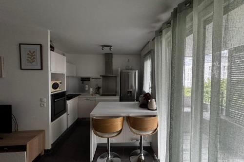 une cuisine avec une table et deux tabourets de bar dans l'établissement Le Piou Vert, à Annecy