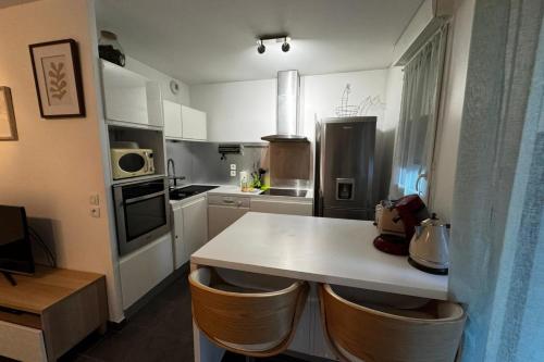 - une cuisine avec un comptoir blanc et des chaises dans l'établissement Le Piou Vert, à Annecy