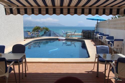 una piscina con mesas y sillas y el océano en Hotel La Riviera, en Albir