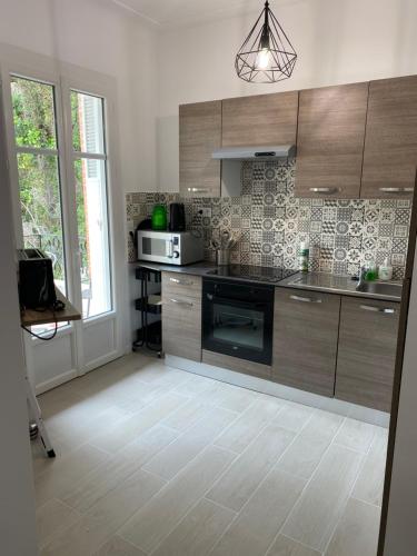 - une cuisine avec des placards en bois et un four micro-ondes dans l'établissement R1G-120 m plage-2 ch-jardin, à Agay