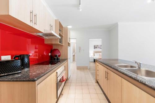 a kitchen with red walls and wooden cabinets at Convenient East Perth Stay with Free Parking in Perth