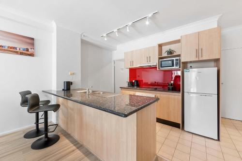 a kitchen with a counter and a sink and a refrigerator at Convenient East Perth Stay with Free Parking in Perth