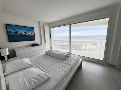une chambre avec un lit et une grande fenêtre dans l'établissement Le Touquet Paris-Plage face mer, prox rue St Jean, à Le Touquet-Paris-Plage