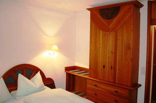 Hotel Rodewisch في Rodewisch: غرفة نوم بسرير وخزانة خشبية