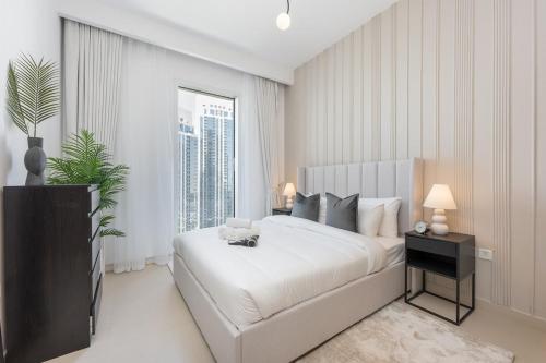 a bedroom with a white bed and a large window at Free housekeeping visits during your stay - StayShort - Captivating 1BR apartment in Dubai Creek Harbour in Dubai