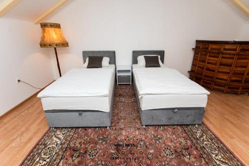two beds in a room with a rug at Heaven Heart - Apartmani Tuzla in Tuzla