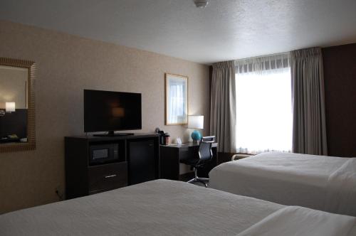 a hotel room with two beds and a flat screen tv at Quality Inn Homestead Park in Billings
