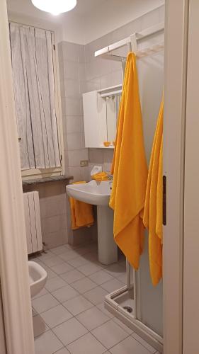ein Badezimmer mit Waschbecken und Toilette und gelben Handtüchern in der Unterkunft Appartamento 93 di andrea sonzogni in Castelleone