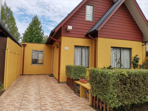 a yellow and red house with a brick driveway at Habitación grande baño en suite privado in Concepción