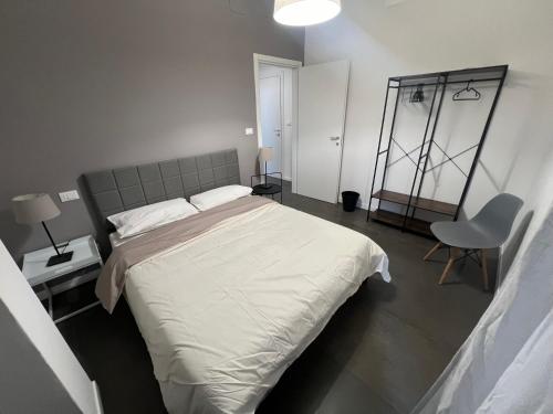 una camera da letto con un grande letto bianco e una sedia di ManaroomsMasini a Bologna