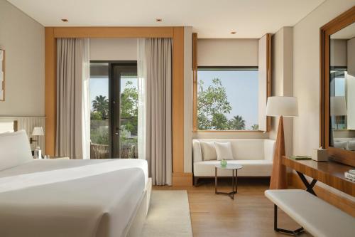 a bedroom with a bed and a couch and a window at Delano Dubai at Bluewaters in Dubai