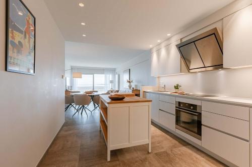 a kitchen with white cabinets and a dining room at Huswell - Seaview apartment with spacious terrace in Zeebrugge in Zeebrugge