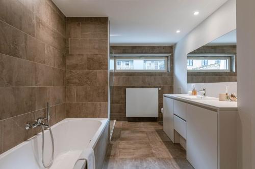 a bathroom with a tub and two sinks at Huswell - Seaview apartment with spacious terrace in Zeebrugge in Zeebrugge