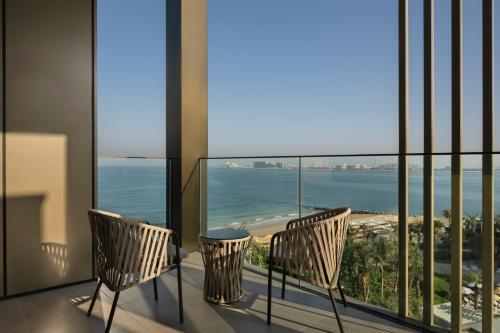 a balcony with two chairs and a view of the ocean at Delano Dubai at Bluewaters in Dubai