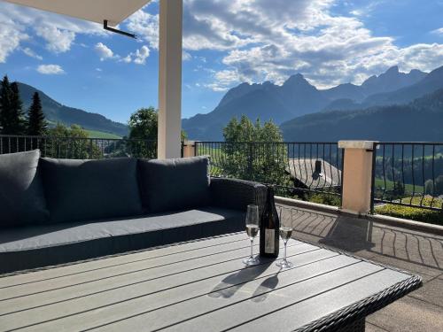 a couch sitting on a table with a glass of wine at Large 3 bed apartment with mountain views, pool and gym in Chateau-d'Oex
