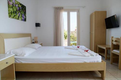 a bedroom with a bed with white sheets and a window at Theologos Beach in Antiparos Town