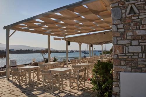 a restaurant with tables and chairs under a wooden pergola at Theologos Beach in Antiparos Town