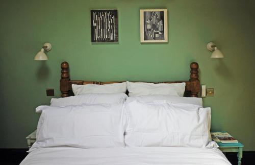 a bedroom with a bed with white pillows and a green wall at Little Hideaway - Central Frome in Frome