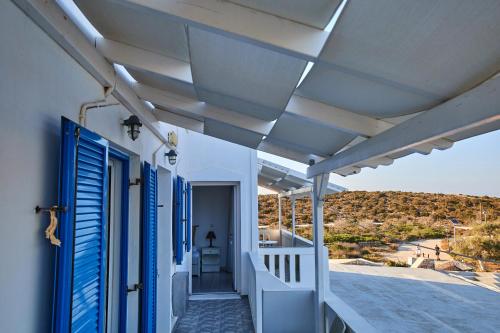 a white house with blue shutters and a balcony at Theologos Beach in Antiparos Town