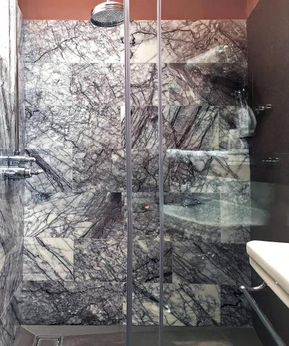 a bathroom with a shower with a marble wall at Little Hideaway - Central Frome in Frome