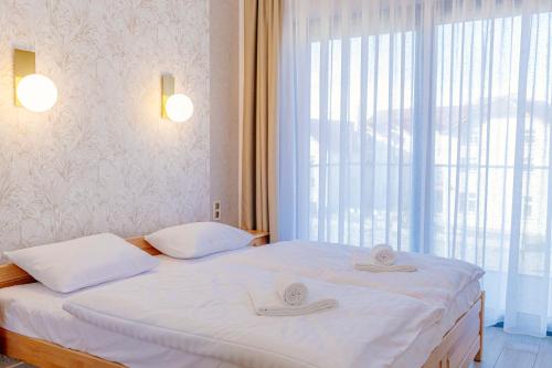 une chambre avec deux lits et une grande fenêtre dans l'établissement Resort Hevenia Mrzeżyno 4, à Mrzeżyno