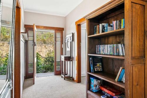 a room with wooden shelves with books at Cascade Cottage adjoining World Heritage Site in Hobart