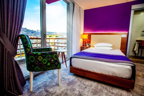 a bedroom with a bed and a chair and a window at Business Palas Otel in Kocaeli