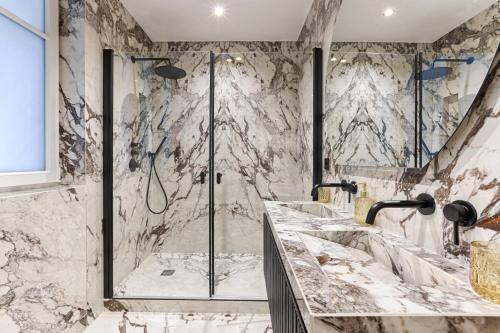 La salle de bains en marbre est pourvue d'une douche et de 2 lavabos. dans l'établissement Elegant Luxury Apartment for 6 on Champs-Élysées, à Paris