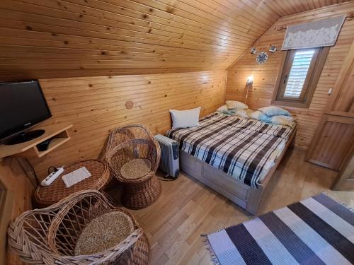 a bedroom with a bed and wicker chairs in a cabin at Nagy Lak II. in Sub Cetate