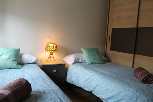 a bedroom with two beds and a lamp on a table at La Cañada in Candeleda