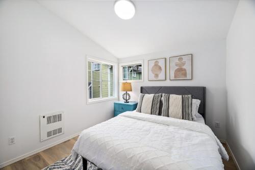 a white bedroom with a bed and two windows at Green Lake Remodelled home with AC garage yard in Seattle