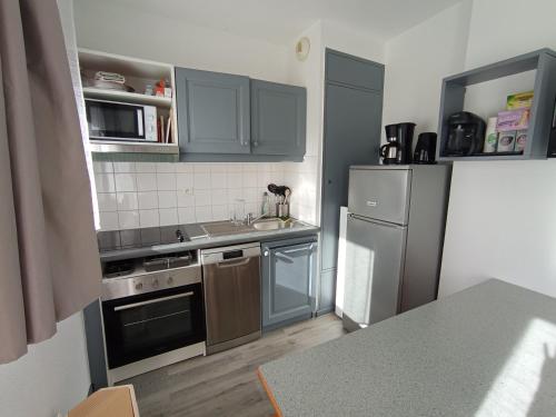 a kitchen with blue cabinets and a sink and a refrigerator at Appart terrasse Superdevoluy in Le Dévoluy