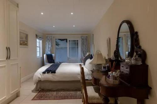 a bedroom with a bed and a desk and a mirror at Langebaan 4 Bedroom Holiday Home in Langebaan