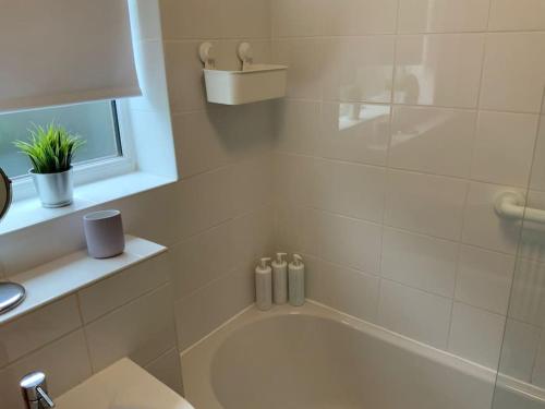 a bathroom with a white tub and a sink at Light and airy cosy bungalow in Draycott