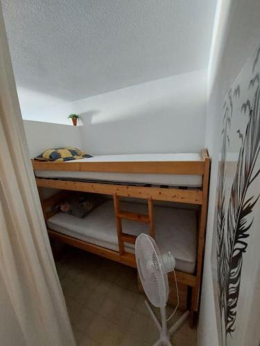 Cette petite chambre dispose de lits superposés et d'un ventilateur. dans l'établissement Appartement à 2 pas de la mer, à Canet