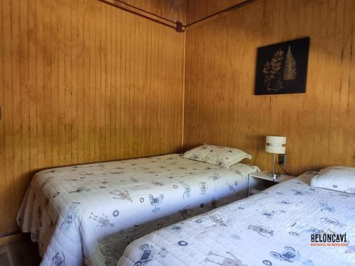 two beds in a room with wooden walls at Ruka Lee I Las Trancas - Refugios de Montaña Reloncaví - Factura Inmediata in Las Trancas