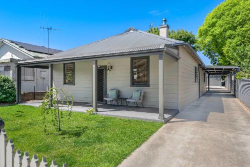 a small white house with two chairs in a yard at Dalton Cottage - Charm & Convenience in Orange