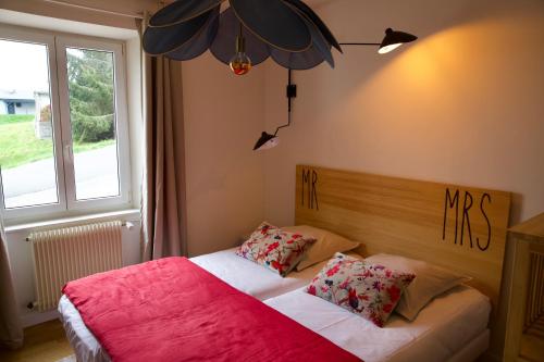 a bedroom with a bed with two pillows and a window at Les deux maisons - Roz - Appartement Gérardmer vue pistes proche lac in Gérardmer
