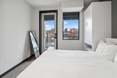 a bedroom with a white bed and a window at CozySuites Mass with parking lounge & roof deck #23 in Indianapolis