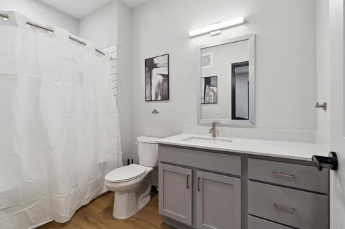 a white bathroom with a toilet and a sink at CozySuites Mass with parking lounge & roof deck #24 in Indianapolis
