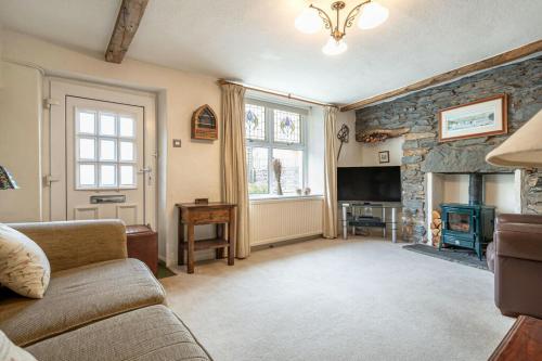 a living room with a couch and a fireplace at Bens Row Cottage, The Lake District in Backbarrow
