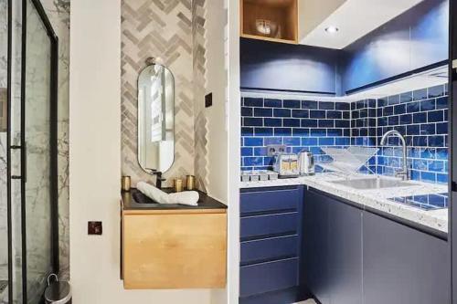 une salle de bain bleue avec un lavabo et un miroir dans l'établissement Charmant loft lumineux avec mezzanine Paris 11 - 4P - FLAT-GUEST, à Paris